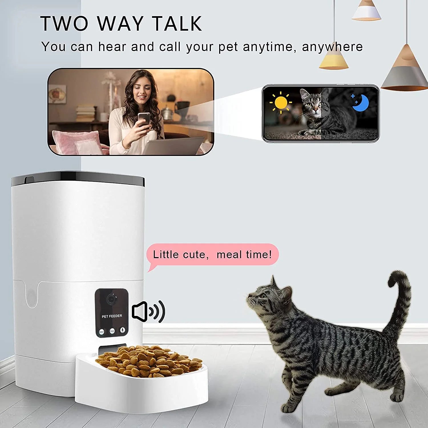 A white automatic pet feeder with a built-in two-way communication system, displaying food in its tray and a gray tabby cat standing nearby. The feeder's screen shows a message saying 'Little cute, meal time!' In the background, there are screenshots of a smartphone video call showing a person interacting with their pet and a view of a cat during day and night. The text 'Two-Way Talk' highlights the feeder's ability to let users hear and call their pet anytime, anywhere.